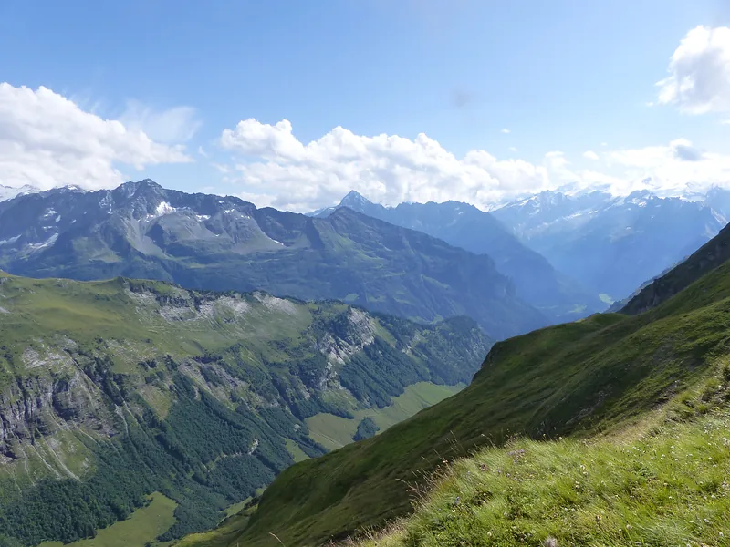 Green high valley with a mountain range and clouds
