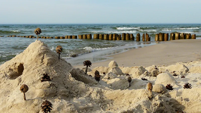 Sandcastles on a beach, groynes in the water behind